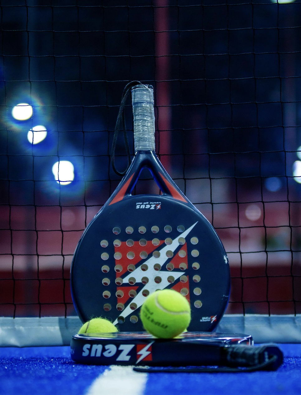 Raquette de Padel posée sur le filet avec des balles