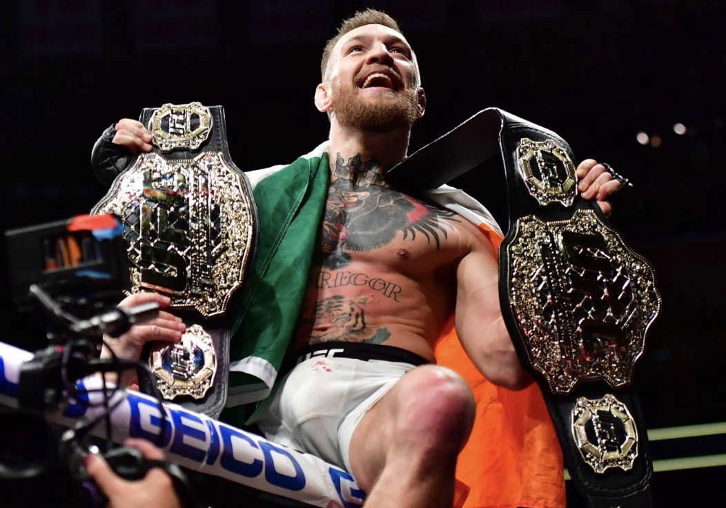 Conor McGregor avec ses deux ceintures de l’UFC sur la cage 