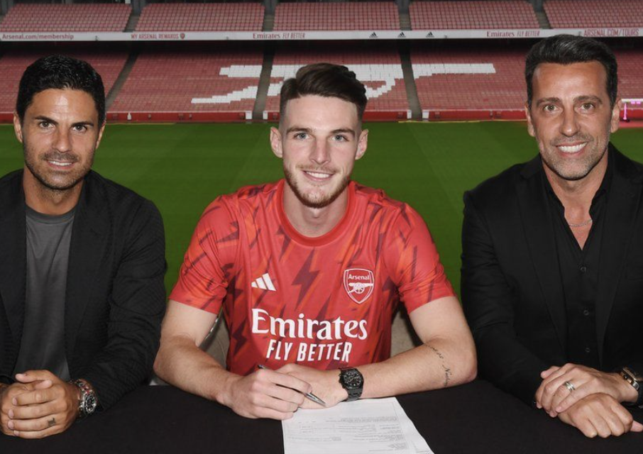 Declan Rice avec un stylo qui signe son contrat avec Arsenal avec Mikel Arteta à ses côtés