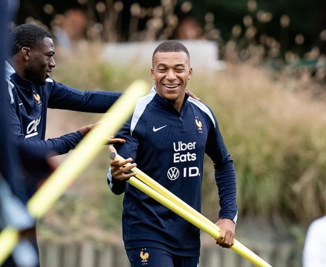 Kylian Mbappé avec les poteaux de corners dans les mains qui rigole à l’entraînement de l’Équipe de France