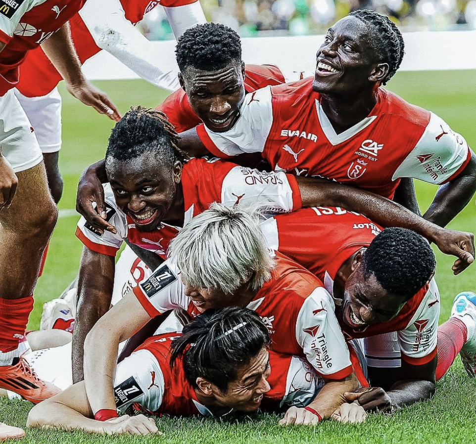 Les joueurs du Stade de Reims se sautent dessus et finissent au sol pour célébrer un but victorieux en Ligue 1