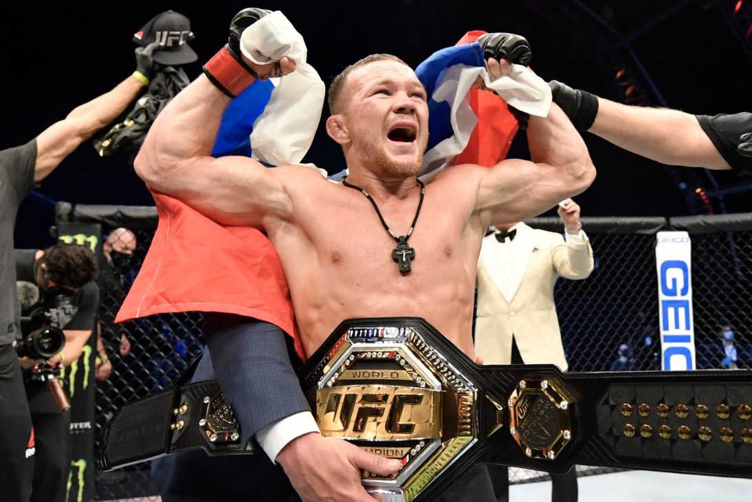 Petr Yan avec le drapeau russe et la ceinture des poids coqs de l’UFC