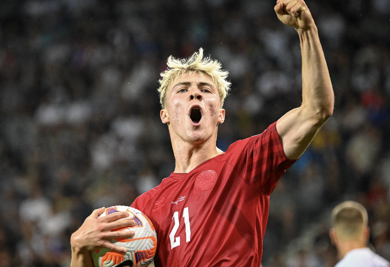 Rasmus Højlund avec le ballon dans la main droite lève le point avec la bouche ouverte vers les supporters du Danemark après son but