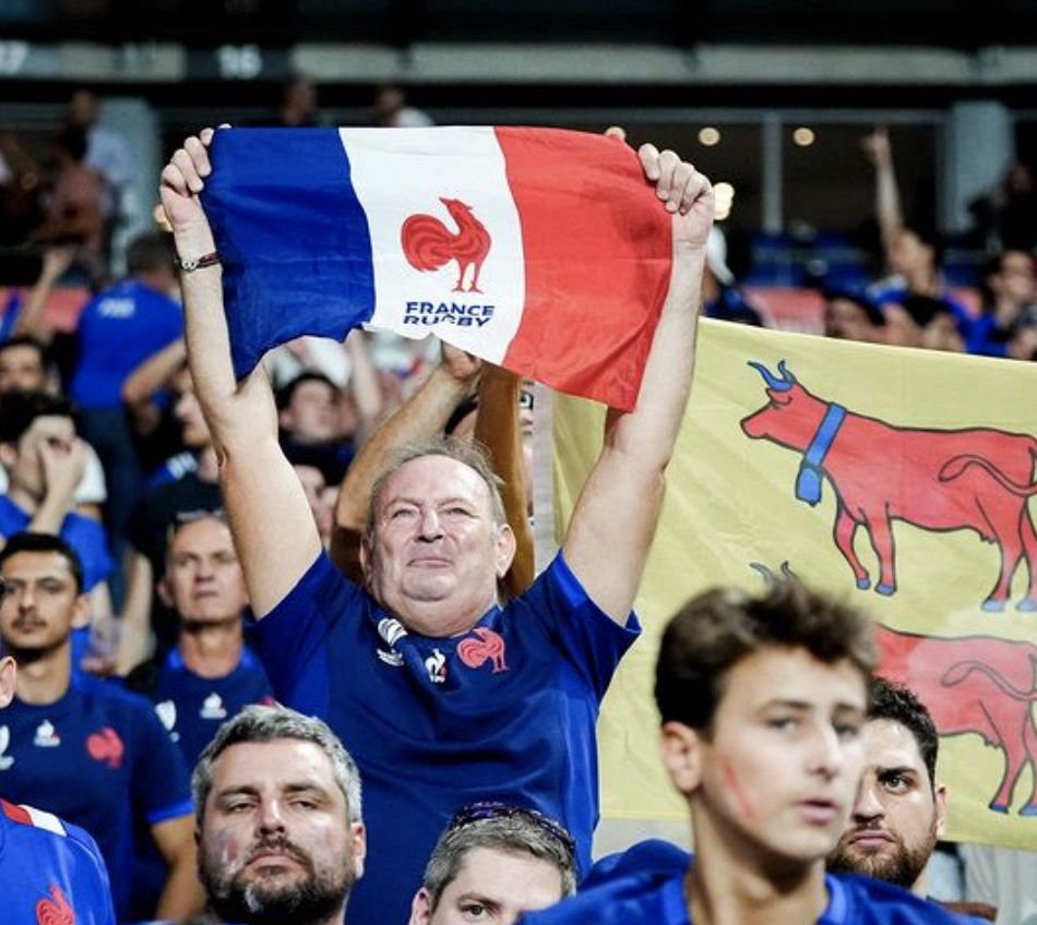 Supporters de l’équipe de France de rugby en tribunes brandissant le drapeau tricolore